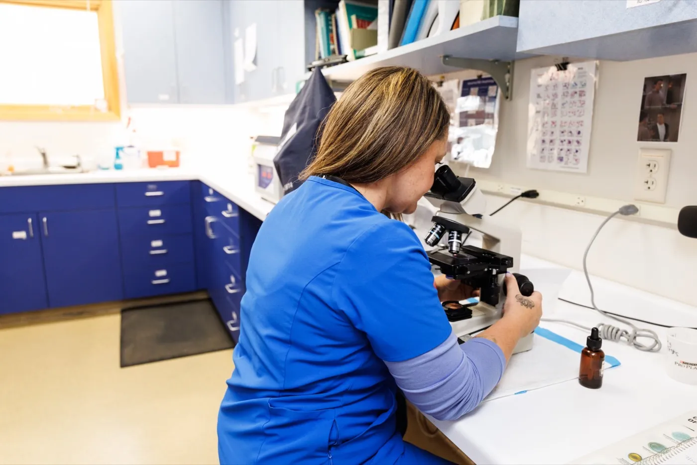 Technician looking through a microscope in the lab